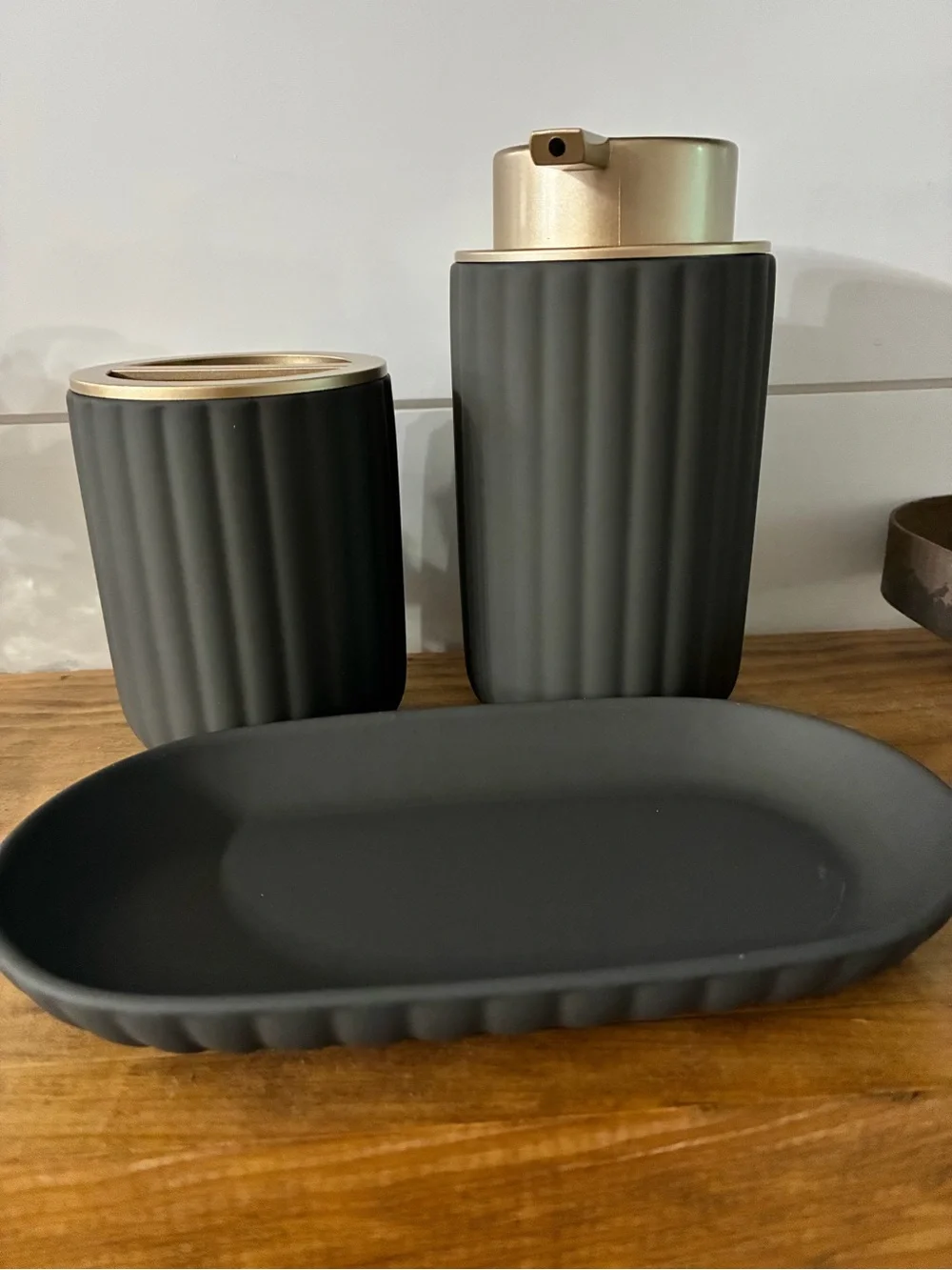 Three-piece matted, charcoal, gray, and gold bathroom accessories